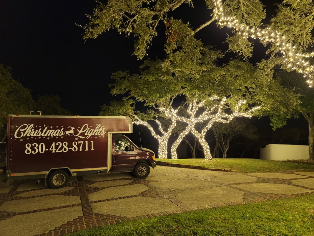 Hill Country Christmas Lights truck beside illuminated trees at night